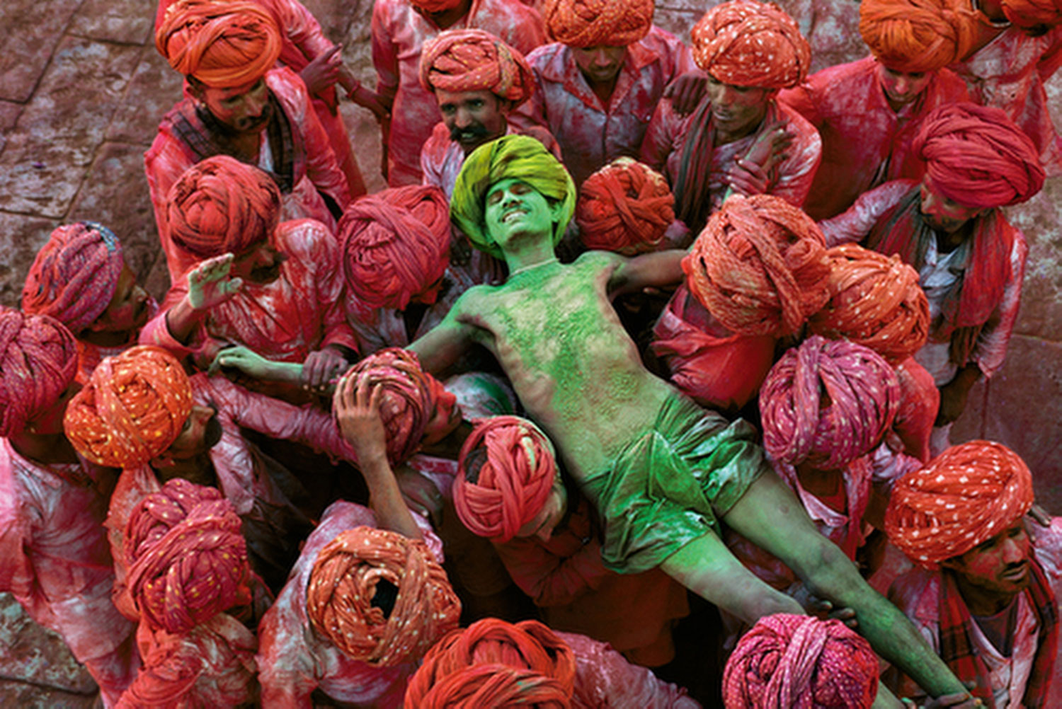 Rajasthan, 1996. A crowd carries a man during the Holi festival. Photograph by Steve McCurry